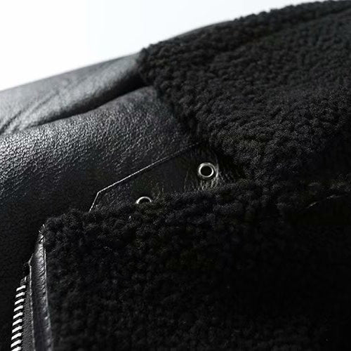 Close-up of a black leather jacket with fur lining on a white background