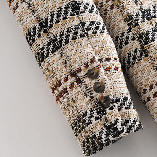Close-up of a tweed fabric sleeve or cuff with a black, beige, and white woven pattern, featuring three dark buttons on a light gray background.