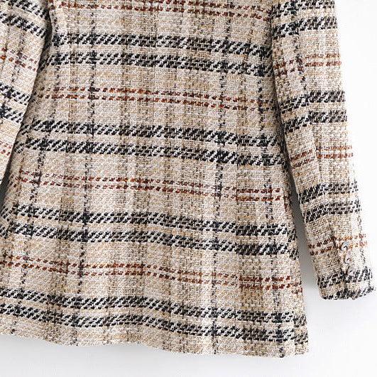 Close-up of a tweed plaid garment, likely a blazer or coat, featuring a textured weave in beige, black, and rust brown.