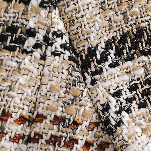 A close-up of a textured tweed fabric with a woven pattern of black, cream, and tan threads, showing the detailed weave and folds.