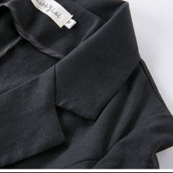 A close-up of olive green fabric folded over itself on a light gray background.