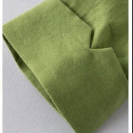 A close-up of olive green fabric folded over itself on a light gray background.