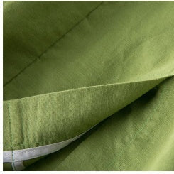 A close-up of olive green fabric folded over itself on a light gray background.