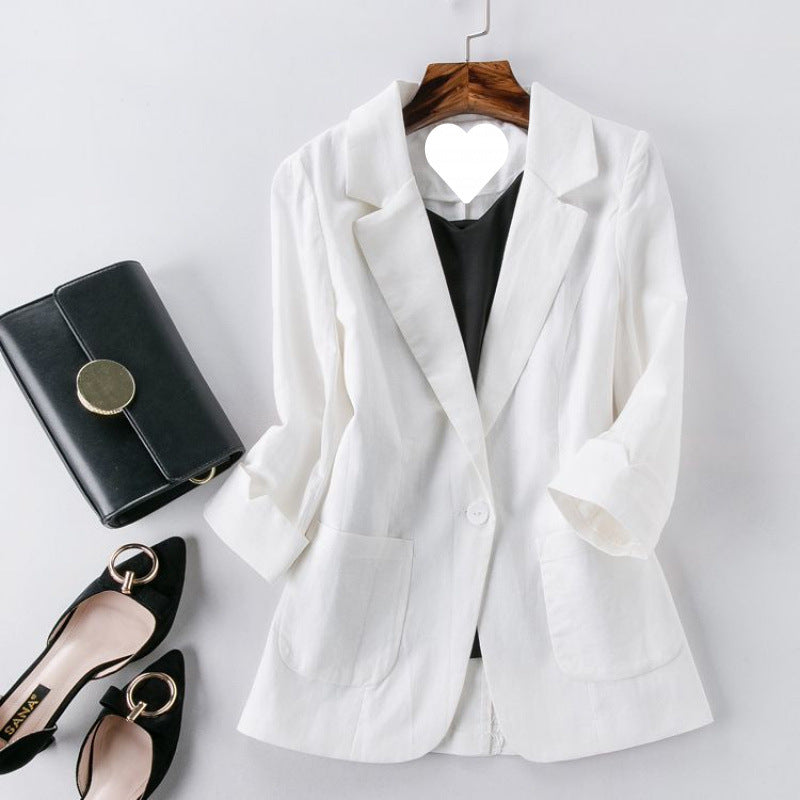White blazer on a hanger with black shoes and handbag on a light gray background