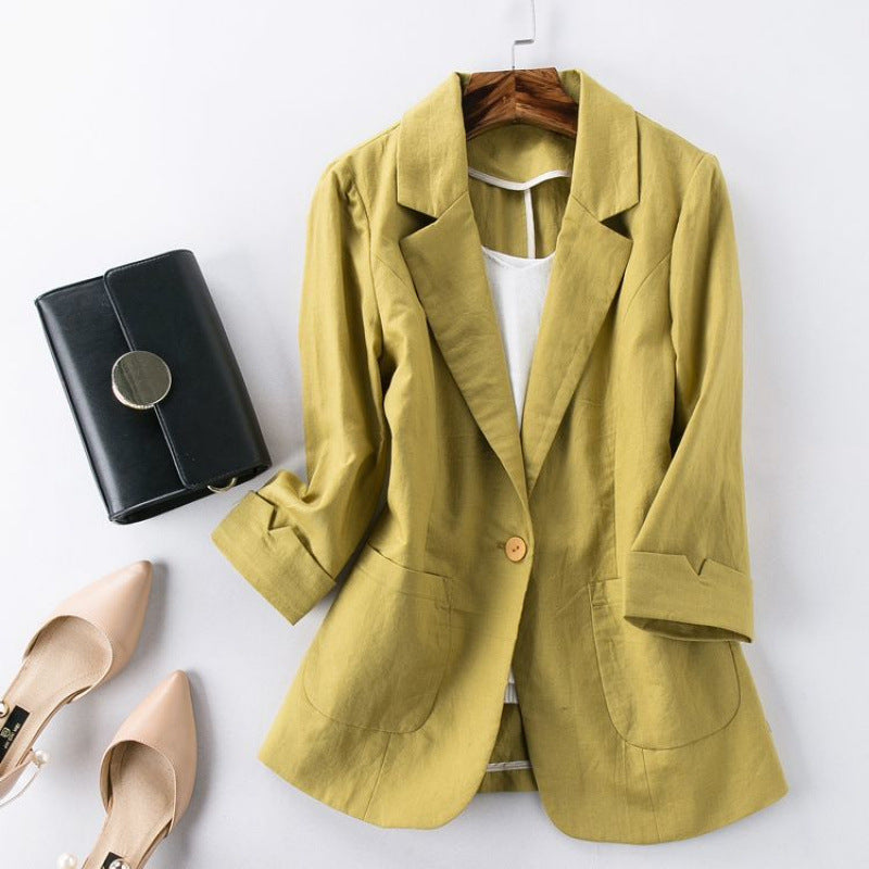 Yellow blazer on a hanger with a black clutch and beige shoes on a white background